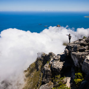 Uno scalatore si accinge a scendere dalla cima di Table mountain. In alto a destra Robben Island, nella cui prigione Nelson Mandela è stato imprigionato per 18 anni (Città del Capo, Sudafrica 2009)