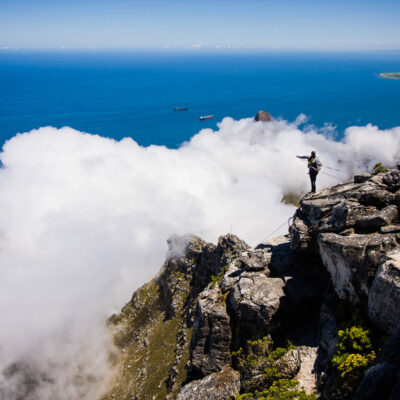 Uno scalatore si accinge a scendere dalla cima di Table mountain. In alto a destra Robben Island, nella cui prigione Nelson Mandela è stato imprigionato per 18 anni (Città del Capo, Sudafrica 2009)