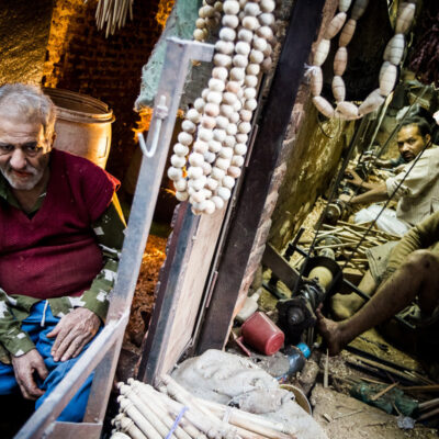 Un uomo mastica paan accanto ad una bottega dove si lavora al tornio a Old Delhi (India 2012)