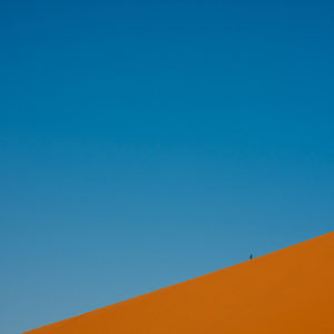 Un fotografo scende da un'alta duna dopo aver raggiunto la cima per ammirare l'alba sul deserto (Merzouga, Marocco, 2010)