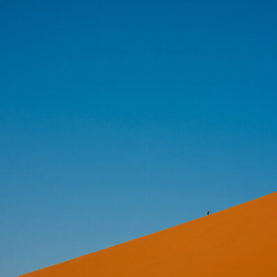 Un fotografo scende da un'alta duna dopo aver raggiunto la cima per ammirare l'alba sul deserto (Merzouga, Marocco, 2010)